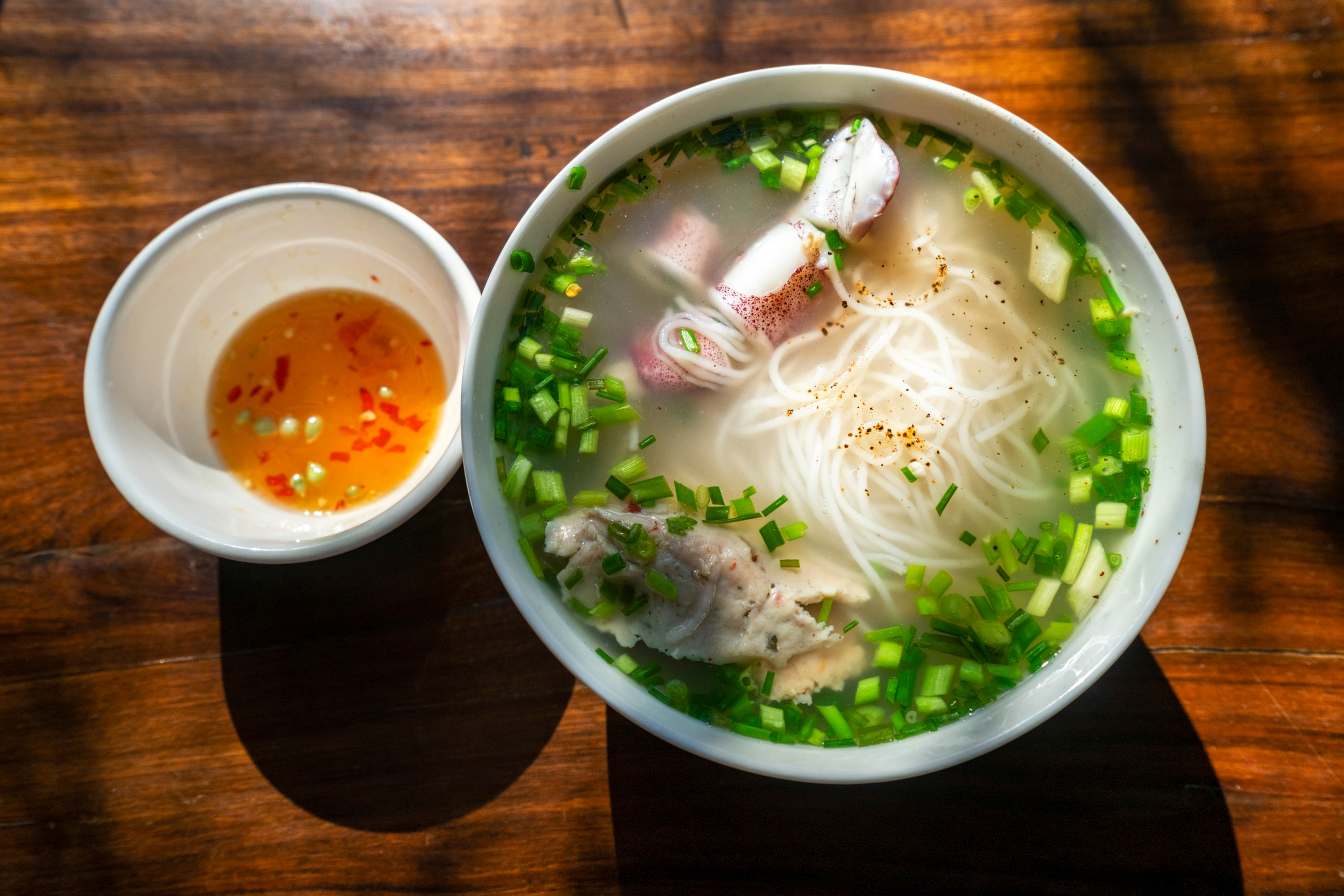 A bowl of Phu Quoc bún quậy with seafood and dipping sauce
